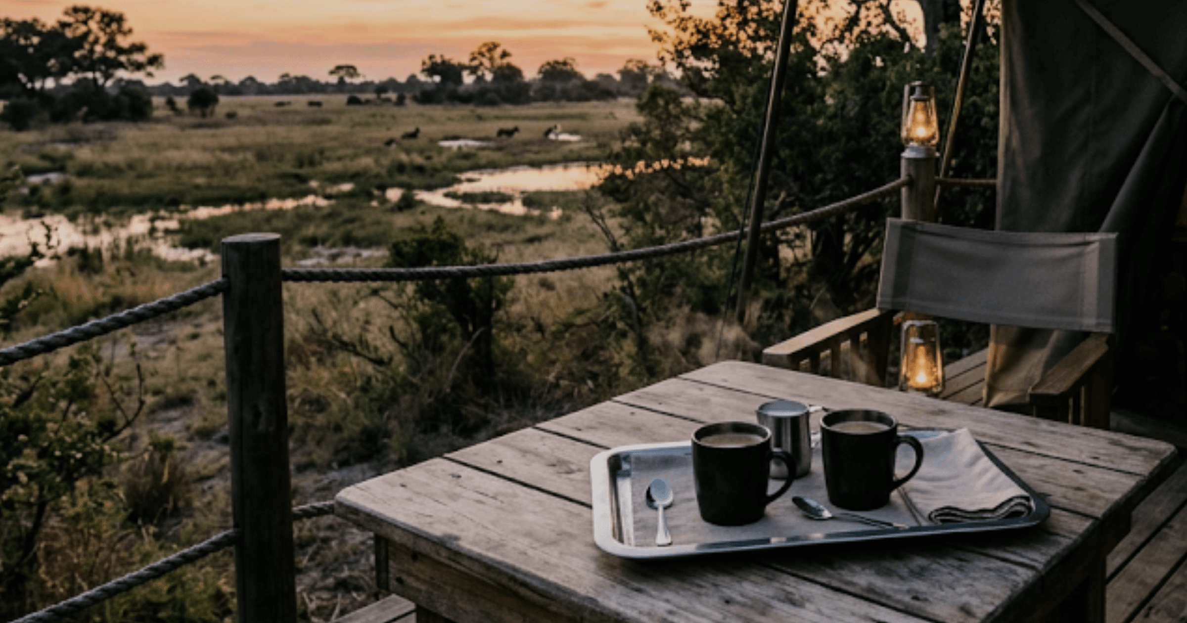 Veranda di un campo safari in Botswana all’alba, con vassoio di caffè e vista sulla savana, inizio di una giornata di safari
